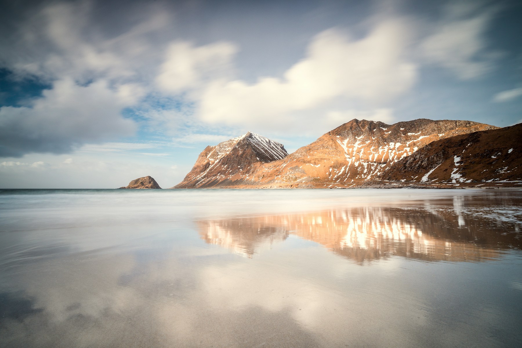Schneebedeckte Berge spiegeln sich im Wasser bei Haukland